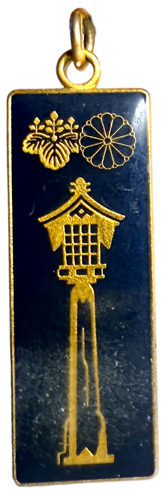 small navy enamel charm with an image of a tiny temple atop a skinny peak in gold